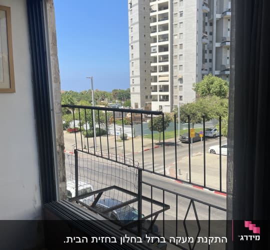 מסגרת חלון עם סורגי מתכת ונוף עירוני